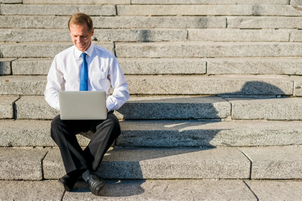 Man in tie using laptop on stone steps