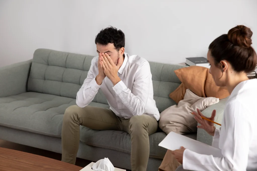 Distressed man covering face in therapy session