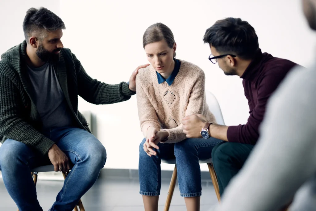 Support group comforting distressed young woman